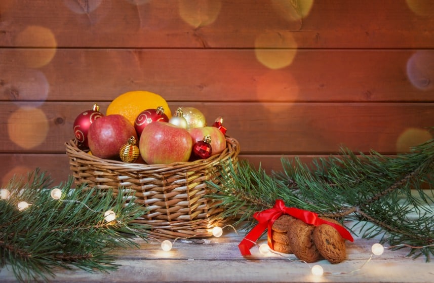 A festive fruit basket next to lights and garland