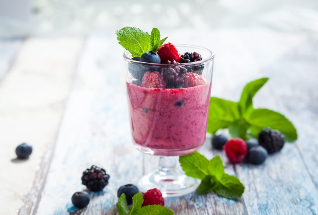 berry smoothies surrounded by raspberries and blackberries