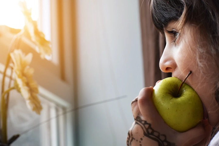 girl biting a green apple