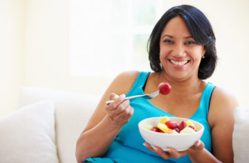 woman eating colorful fruit salad with strawberries