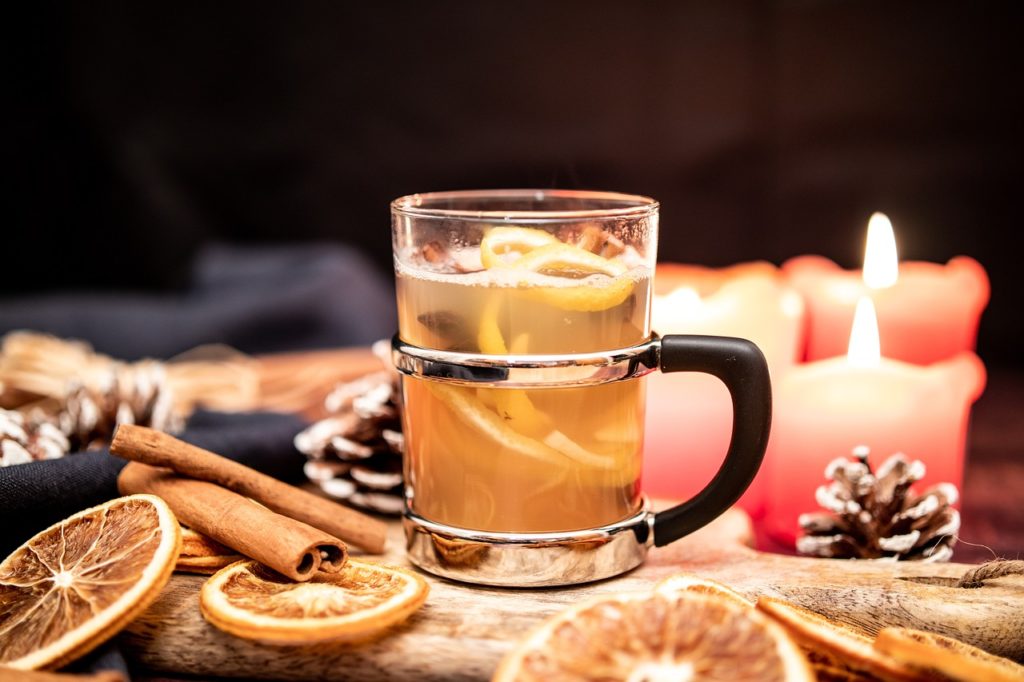 Apple cider cocktail with candles, citrus, and cinnamon sticks