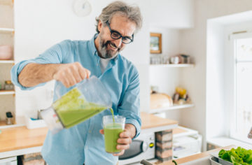 a man in a blue shirt holding a green smoothie