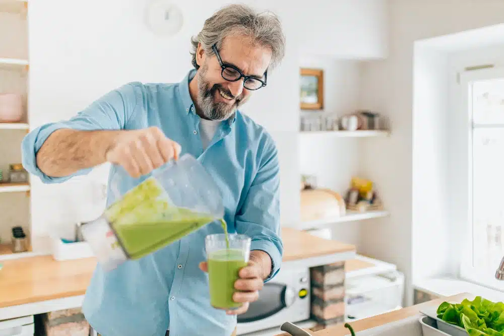 a man pouring a green smoothie into a glass