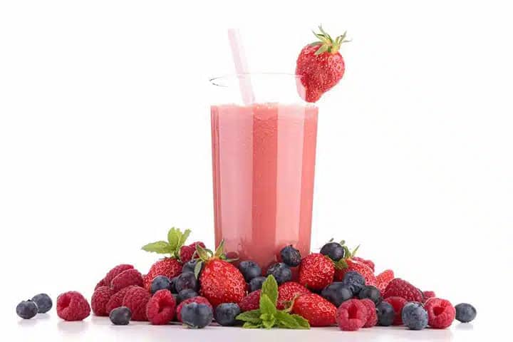 a strawberry fruit smoothie with berries all around it